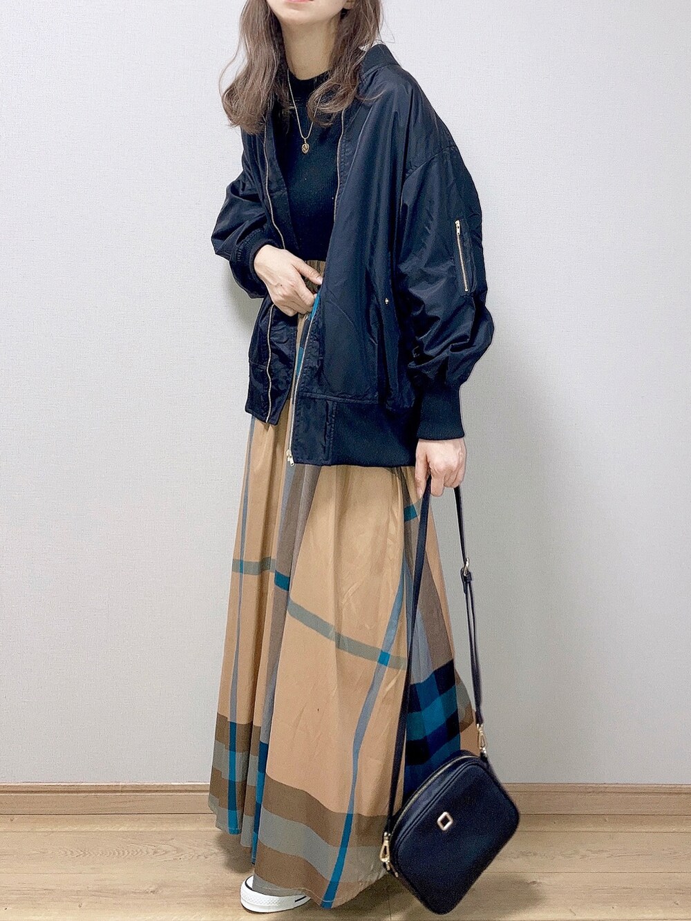 ブラック系のブルゾン、ブラック系のニット/セーター、イエロー系のスカートを着用したレディースの冬コーディネートの2枚目の写真