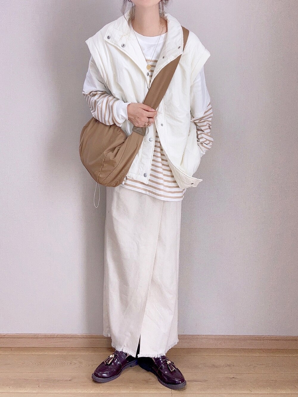 ホワイト系のダウンジャケット/コート、ベージュ系のTシャツ/カットソー、ベージュ系のスカートを着用したレディースの秋コーディネートの2枚目の写真