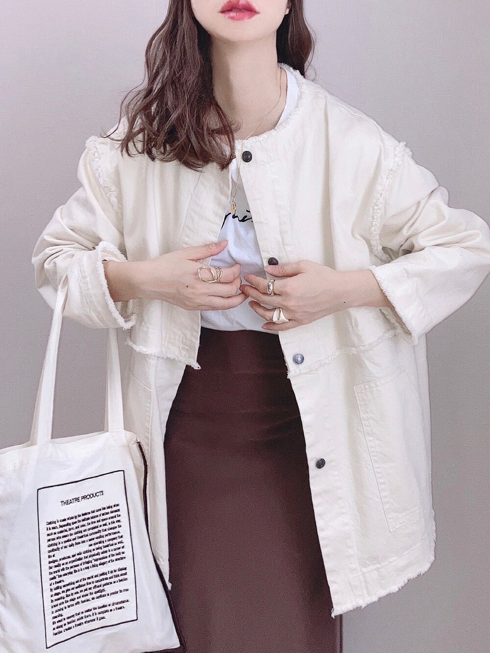 ホワイト系のデニムジャケット、ベージュ系のトートバッグ、ブラウン系のスカートを着用したレディースの冬コーディネートの2枚目の写真