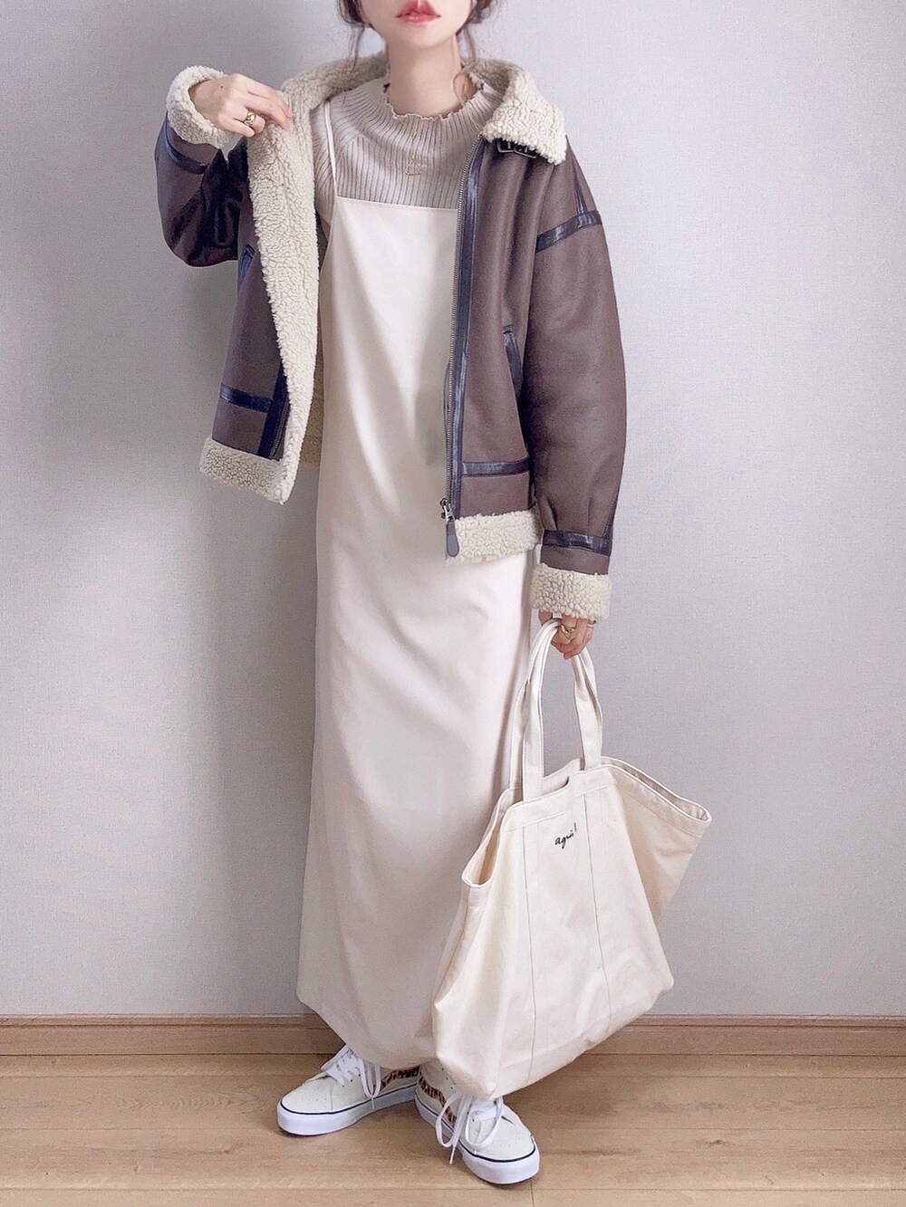 ブラウン系のムートンコート、ブラウン系のニット/セーター、ホワイト系のワンピースを着用したレディースの秋コーディネートの2枚目の写真