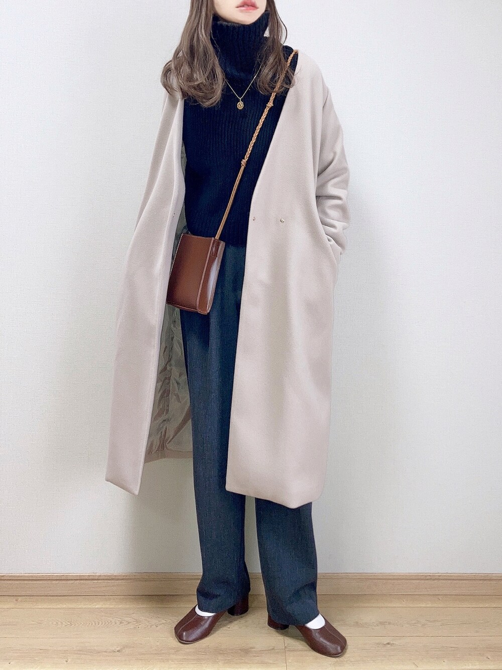 グレー系のノーカラーコート、ブラック系のニット/セーター、グレー系のその他パンツを着用したレディースの冬コーディネートの2枚目の写真