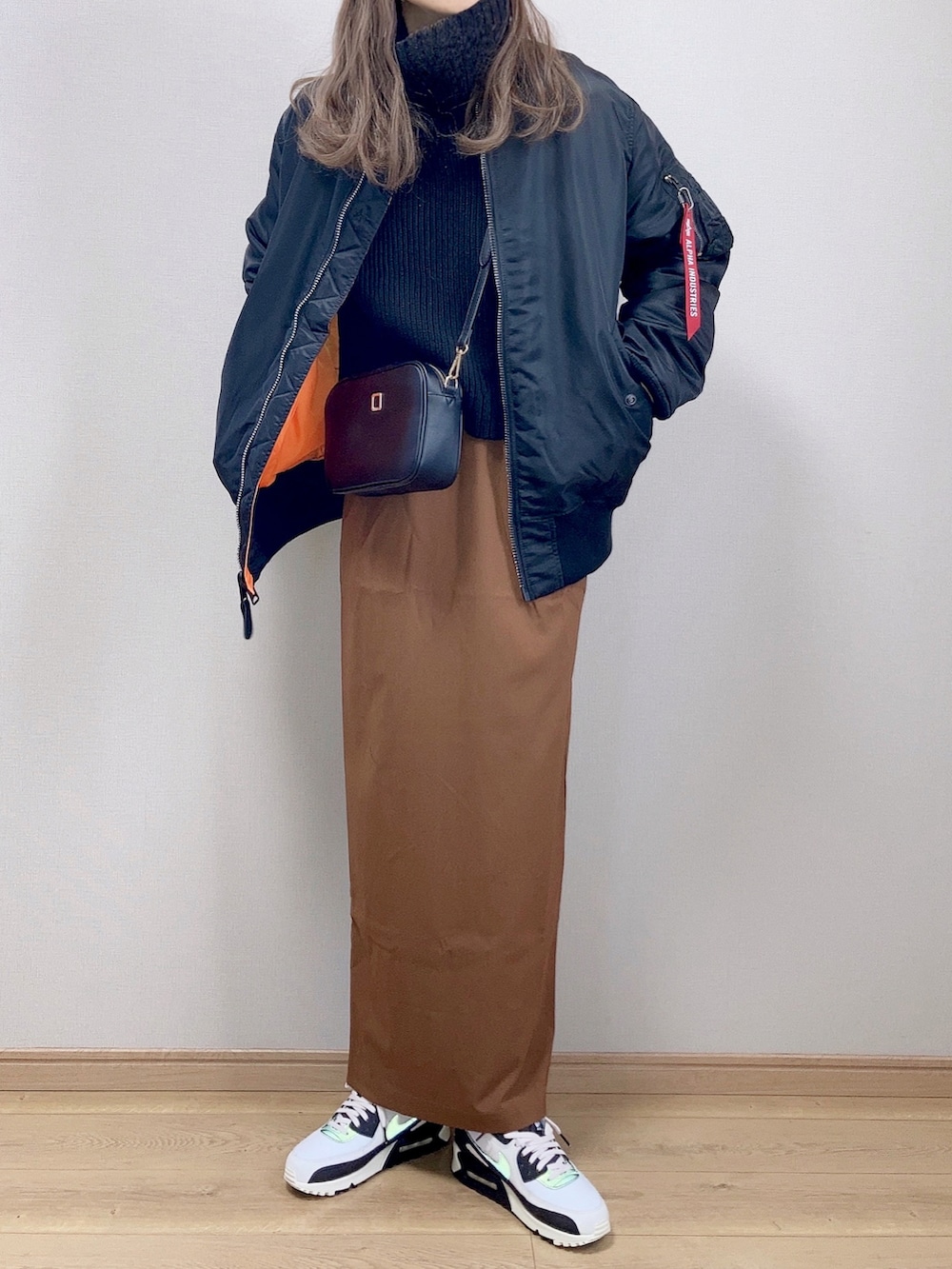 ブラック系のMA-1、ブラウン系のスカート、ブラック系のショルダーバッグを着用したレディースの冬コーディネートの2枚目の写真