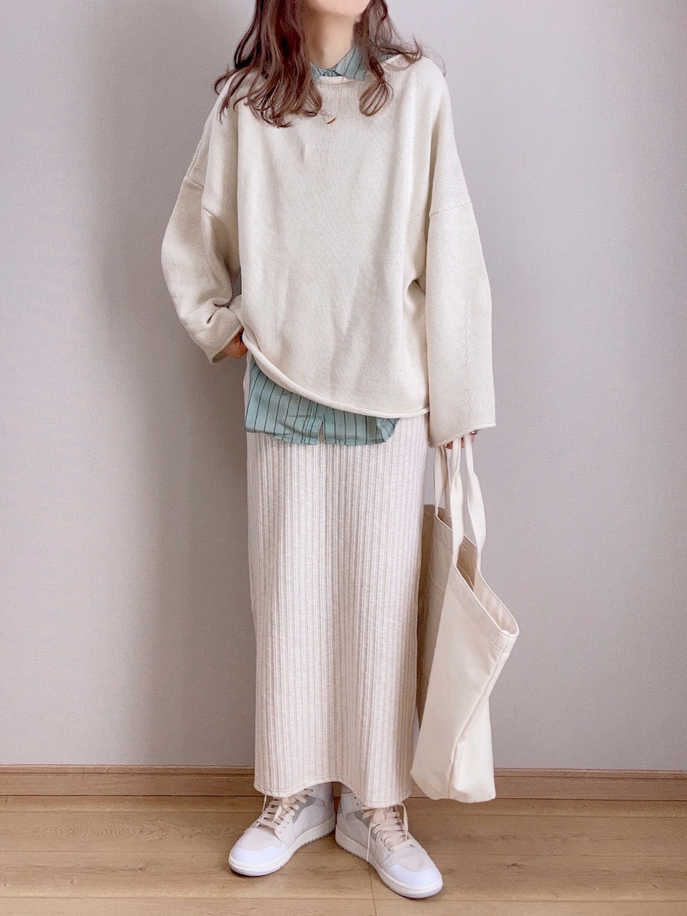 ホワイト系のスカート、ホワイト系のニット/セーター、グリーン系のシャツ/ブラウスを着用したレディースの冬コーディネートの2枚目の写真