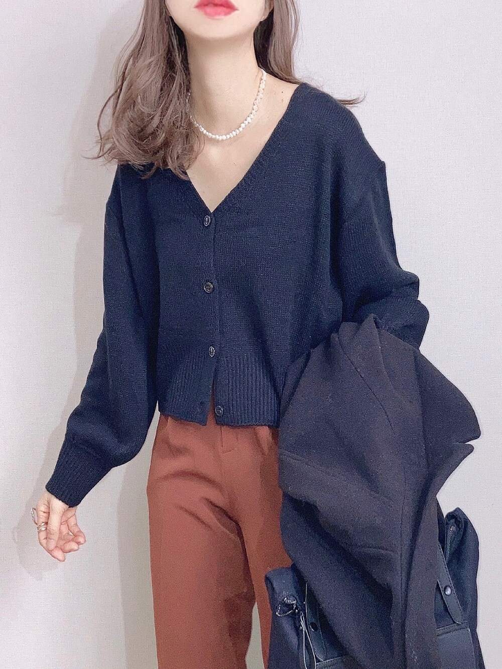 ブラック系のカーディガン/ボレロ、オレンジ系のスラックス、ブラック系のバックパック/リュックを着用したレディースの冬コーディネートの2枚目の写真
