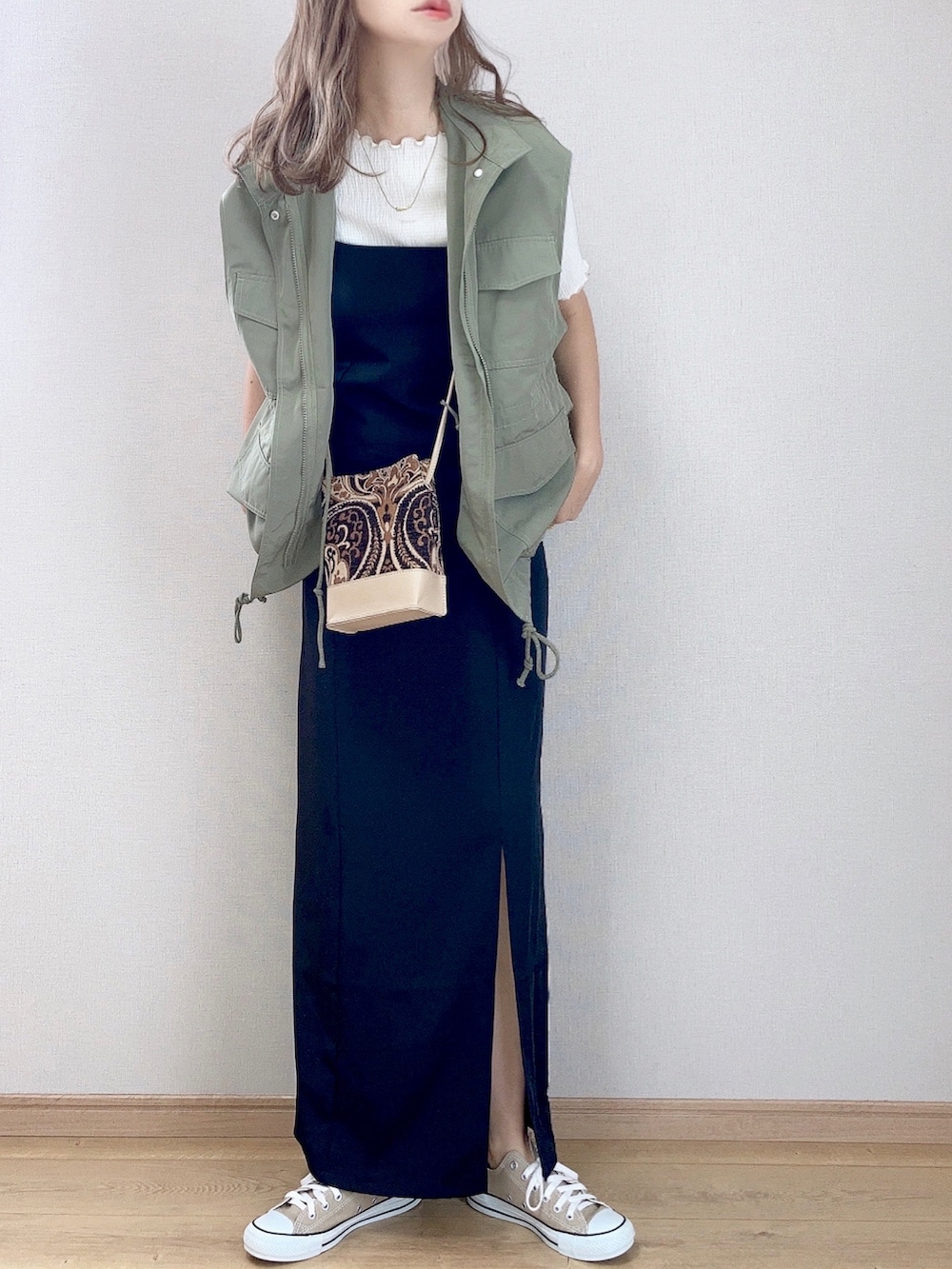 グリーン系のベスト、ホワイト系のTシャツ/カットソー、ブラック系のワンピースを着用したレディースの夏コーディネートの2枚目の写真