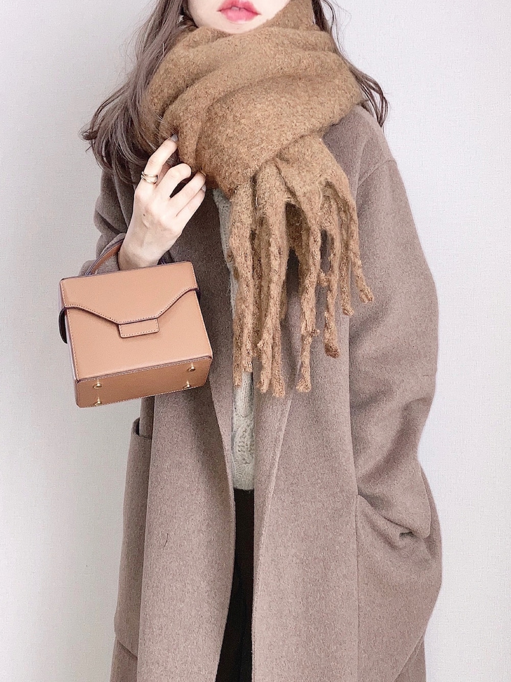 ブラウン系のショルダーバッグ、ブラウン系のピーコート、ホワイト系のニット/セーターを着用したレディースの冬コーディネートの2枚目の写真