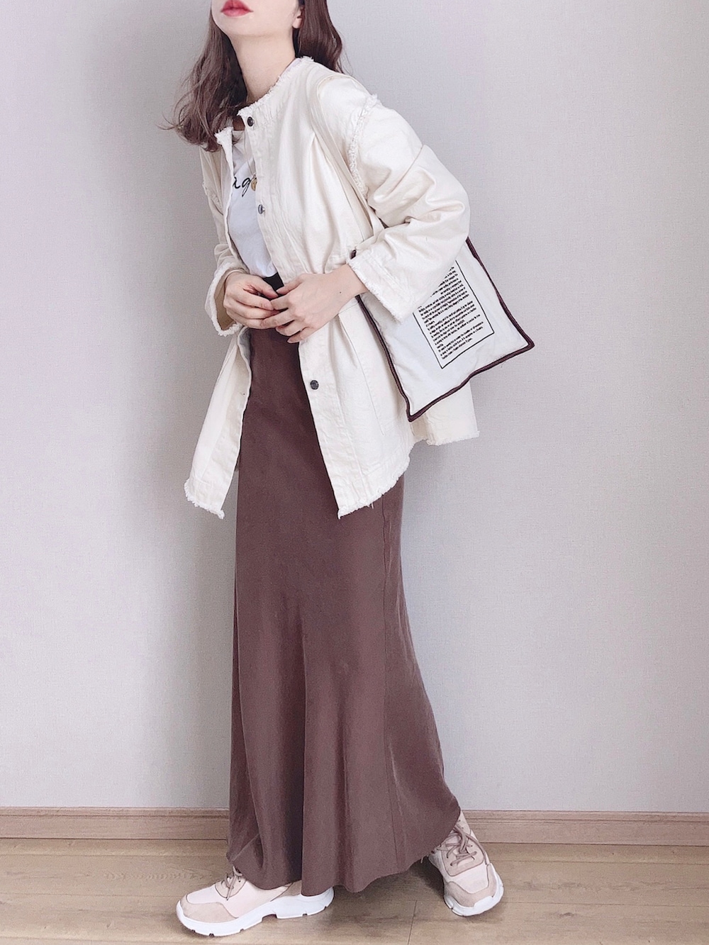 ホワイト系のデニムジャケット、ベージュ系のトートバッグ、ブラウン系のスカートを着用したレディースの冬コーディネートの3枚目の写真