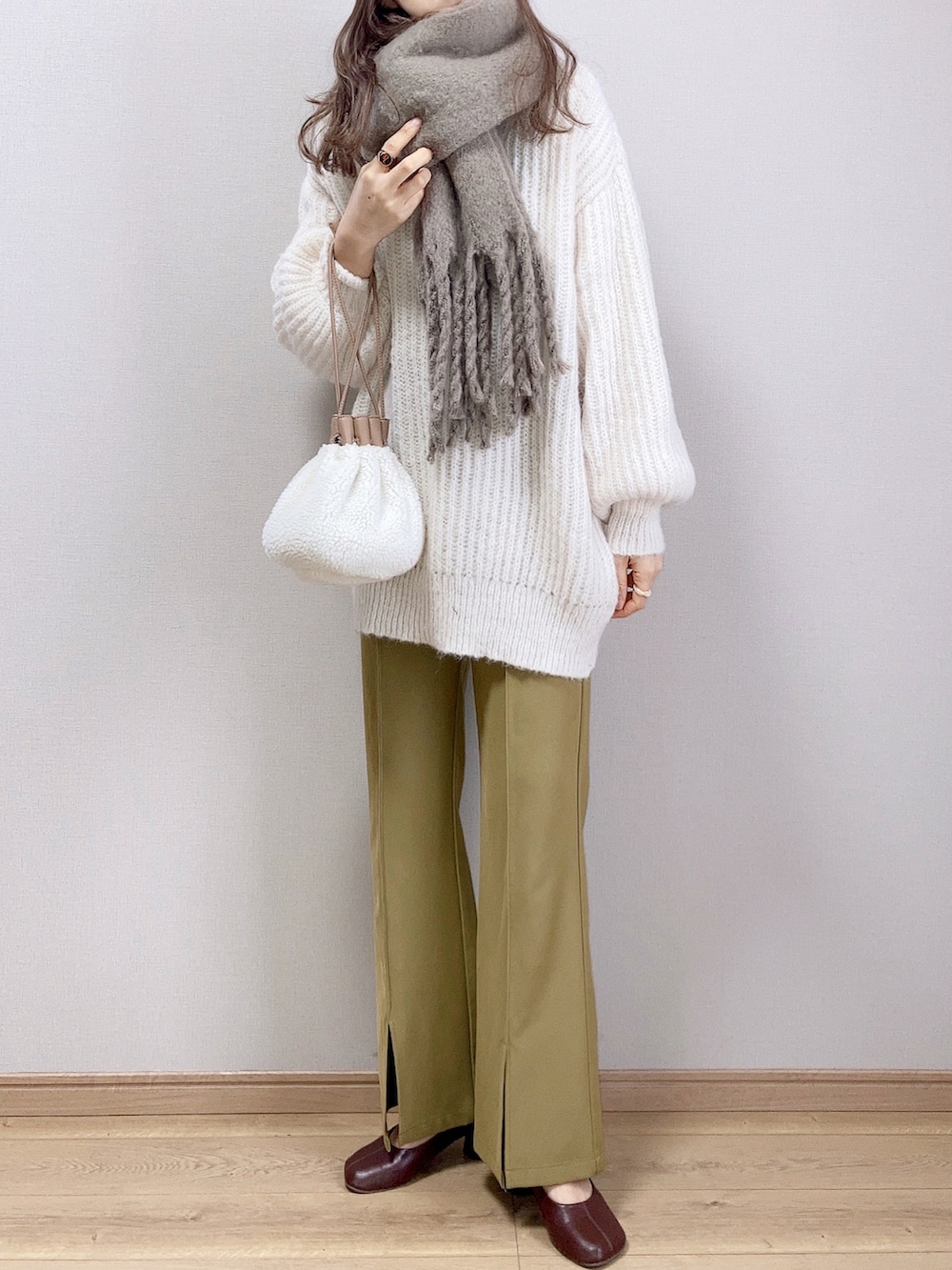 ホワイト系のカーディガン/ボレロ、ベージュ系のハンドバッグ、グリーン系のスラックスを着用したレディースの冬コーディネートの2枚目の写真