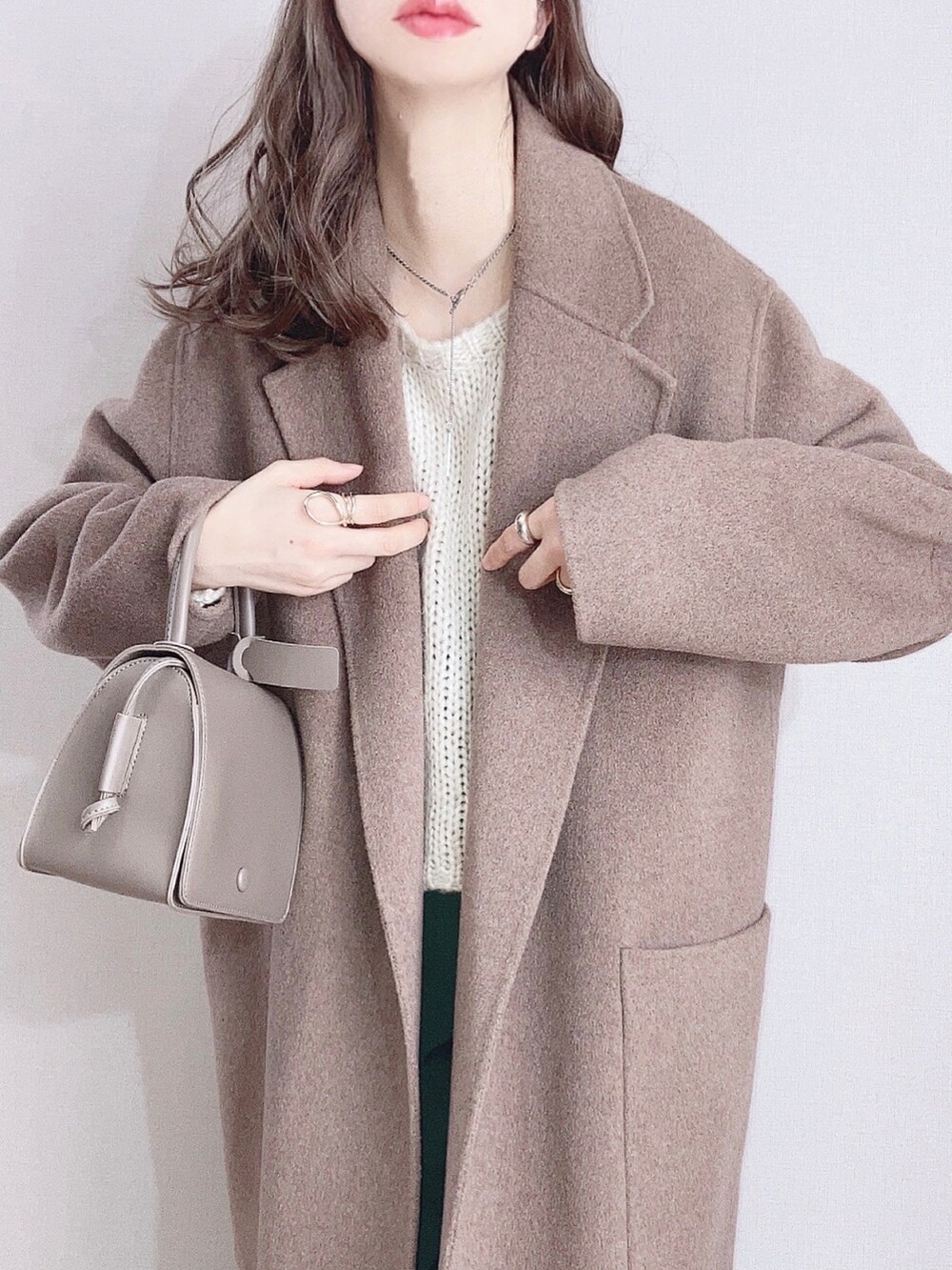 ブラウン系のピーコート、ホワイト系のニット/セーター、グリーン系のスラックスを着用したレディースの冬コーディネートの2枚目の写真