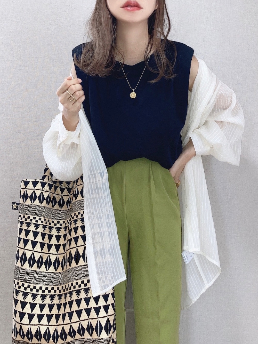 グリーン系のスラックス、ホワイト系のシャツ/ブラウス、ブラック系のタンクトップを着用したレディースの夏コーディネートの2枚目の写真