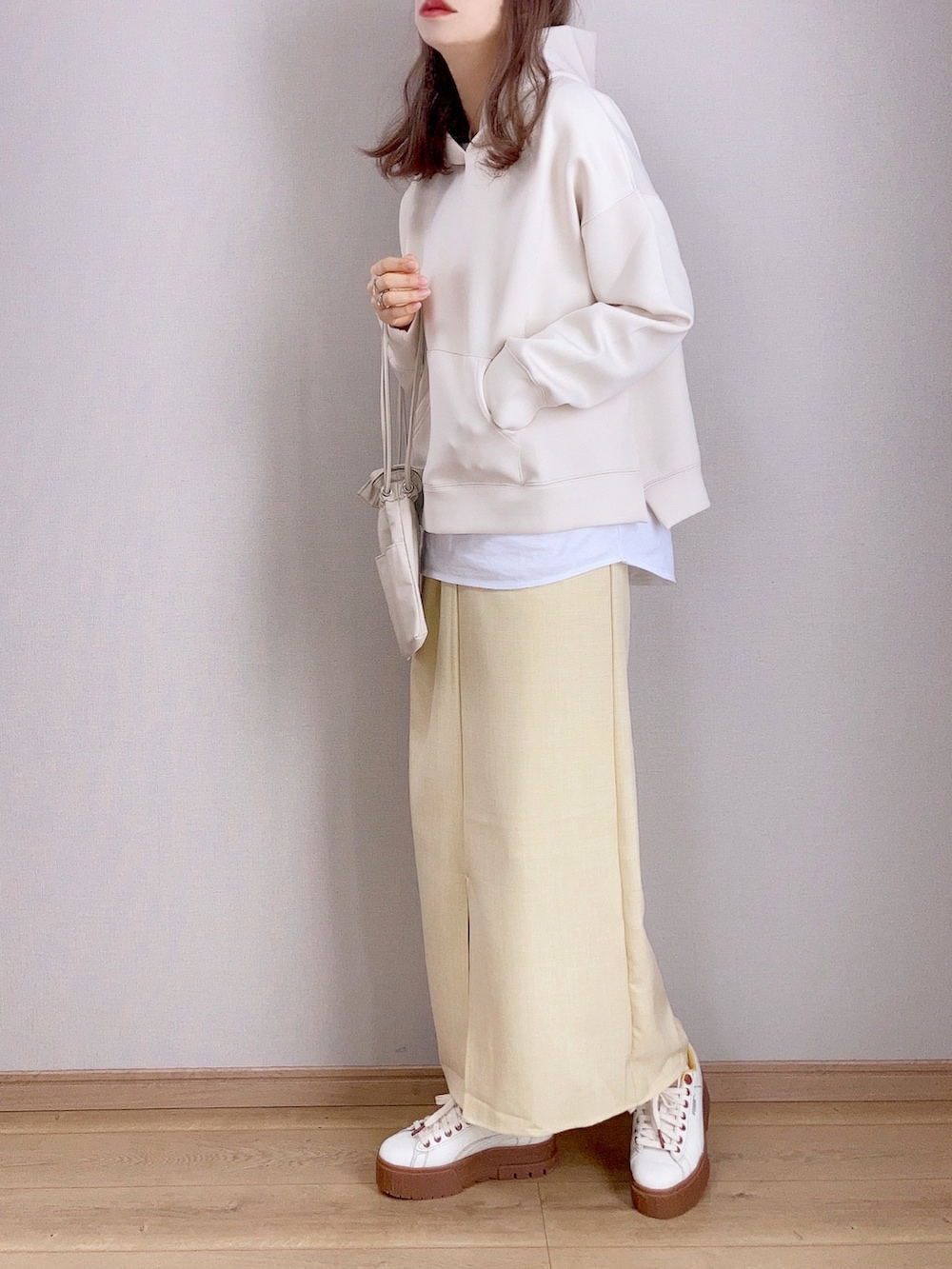 ベージュ系のパーカー、イエロー系のスカート、ベージュ系のショルダーバッグを着用したレディースの冬コーディネートの2枚目の写真