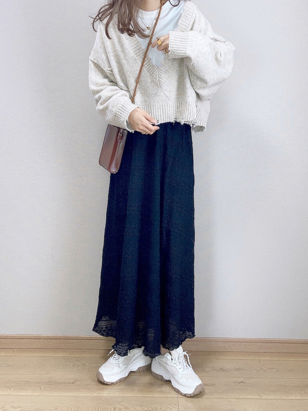 ブラック系のスカート、ホワイト系のニット/セーター、ブラウン系のショルダーバッグを着用したレディースの秋コーディネートの2枚目の写真