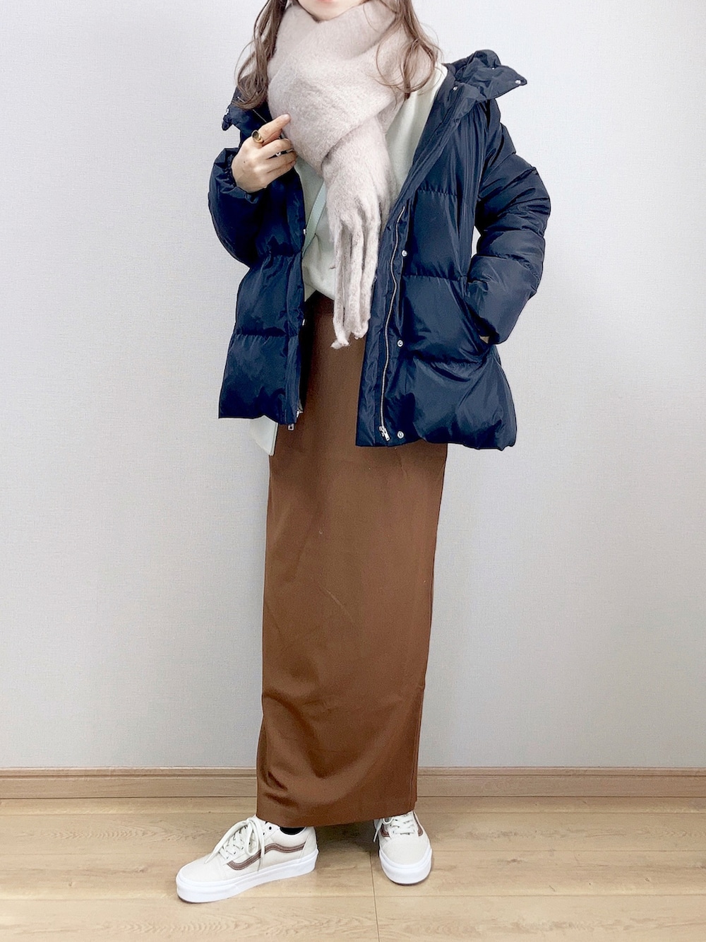 ブラック系のダウンジャケット/コート、ベージュ系のスウェット、ブラウン系のスカートを着用したレディースの冬コーディネートの2枚目の写真