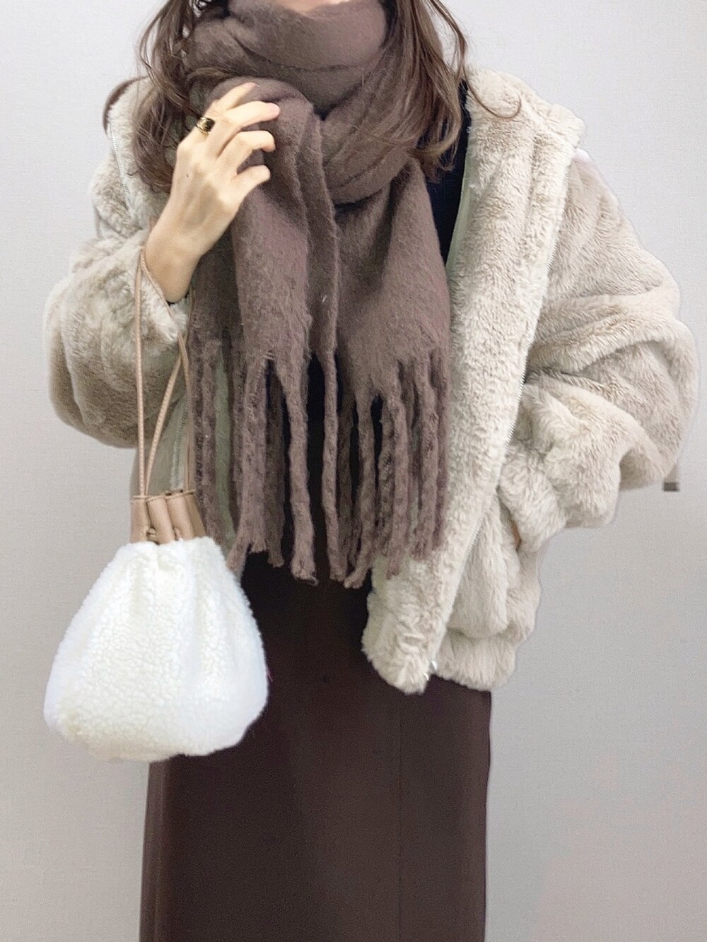 ベージュ系のブルゾン、ブラウン系のスカート、ベージュ系のハンドバッグを着用したレディースの冬コーディネートの3枚目の写真