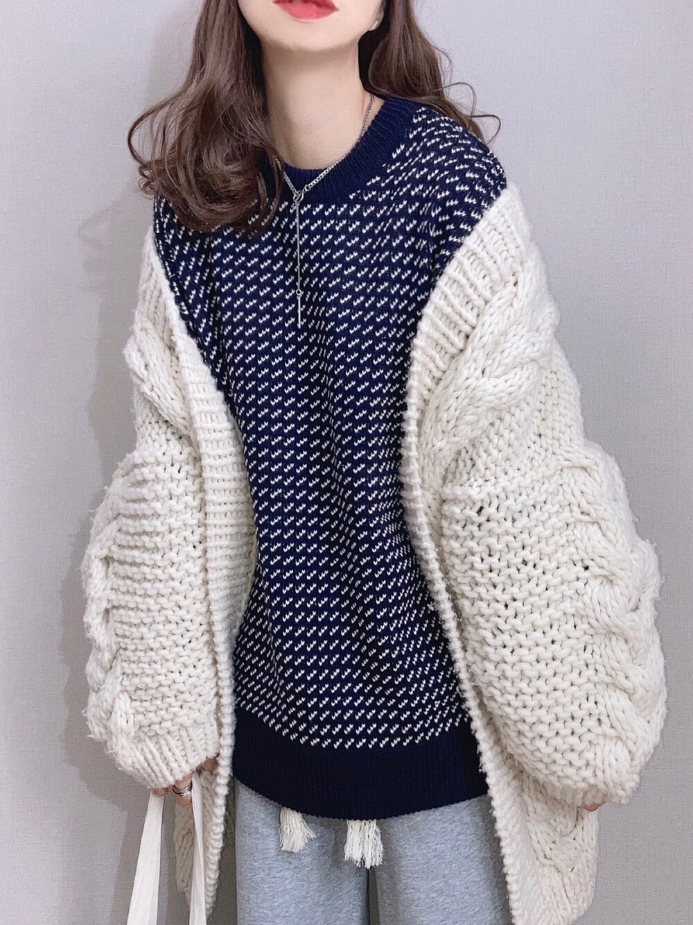 ブルー系のニット/セーター、ホワイト系のカーディガン/ボレロ、グレー系のスウェットパンツを着用したレディースの冬コーディネートの2枚目の写真