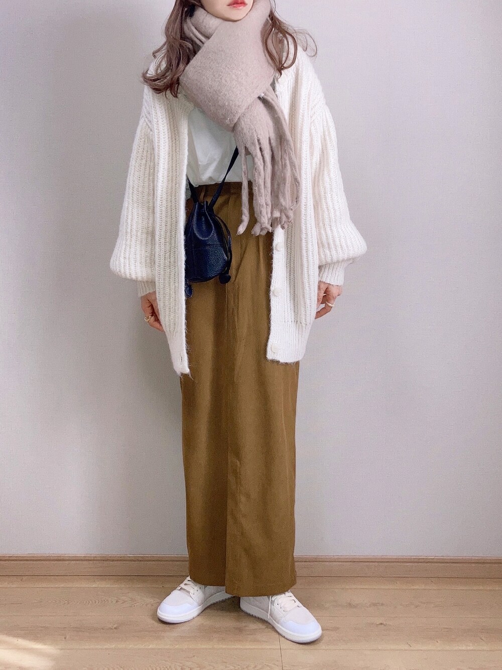 ホワイト系のカーディガン/ボレロ、ブラウン系のスカート、ブラック系のショルダーバッグを着用したレディースの冬コーディネートの2枚目の写真