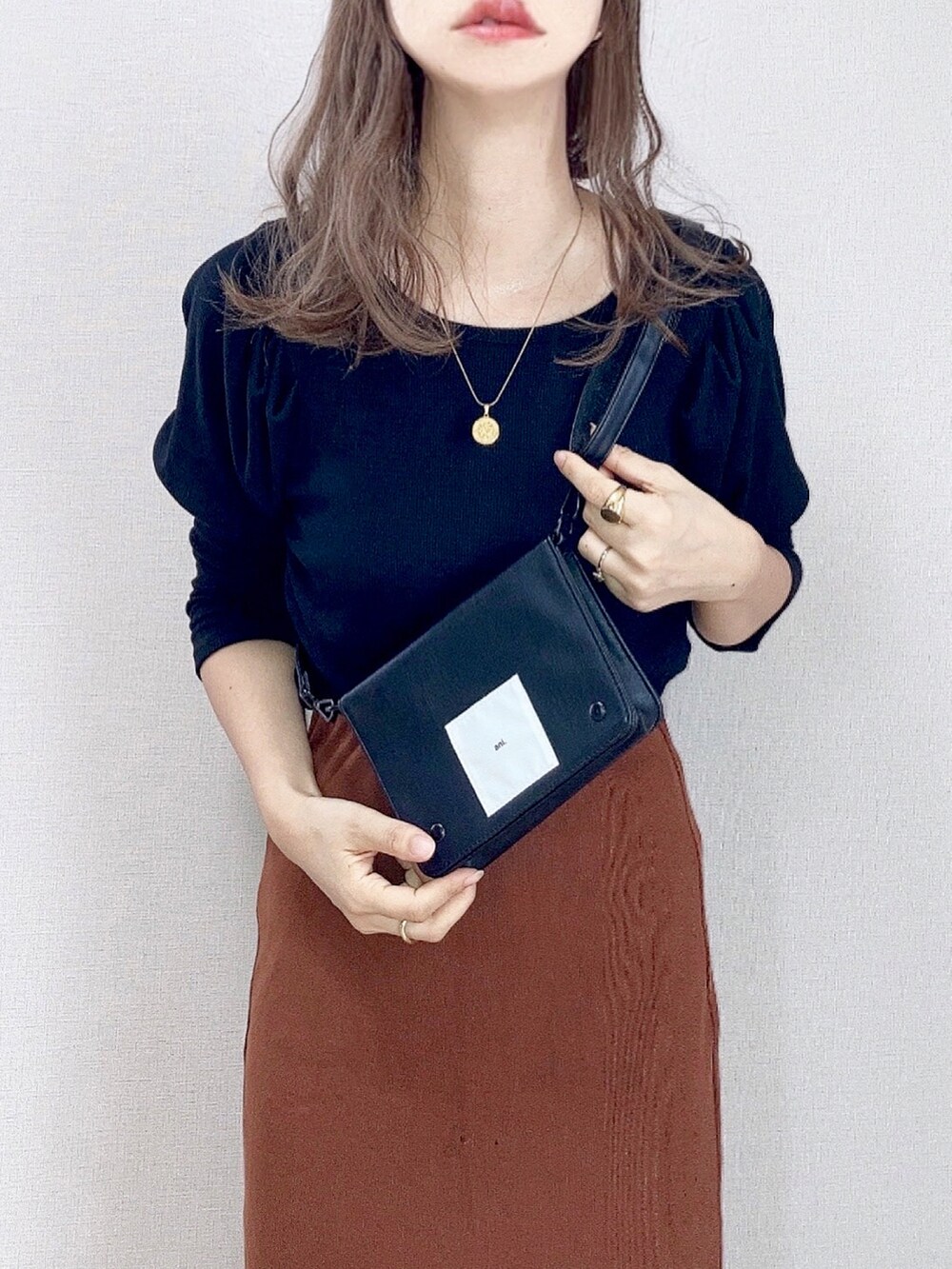 ブラック系のTシャツ/カットソー、ブラウン系のスカート、ブラック系のショルダーバッグを着用したレディースの秋コーディネートの2枚目の写真