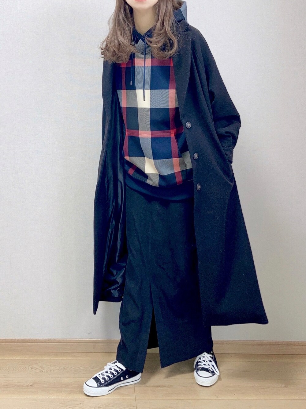 ブルー系のパーカー、ブラック系のチェスターコート、ブラック系のスカートを着用したレディースの冬コーディネートの2枚目の写真
