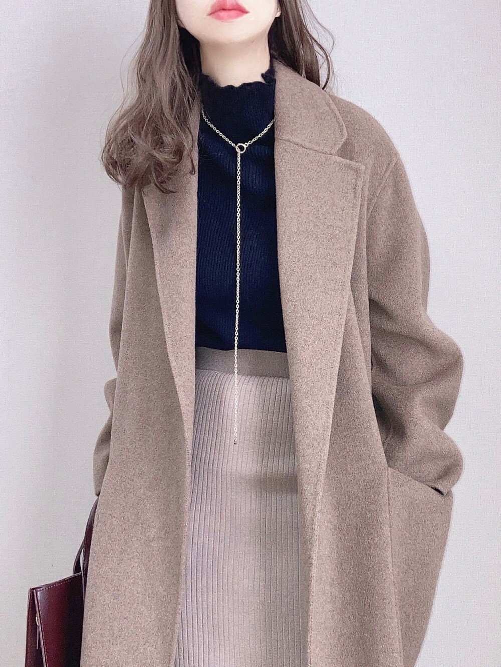 ブラウン系のピーコート、ブラック系のニット/セーター、ベージュ系のスカートを着用したレディースの冬コーディネートの3枚目の写真