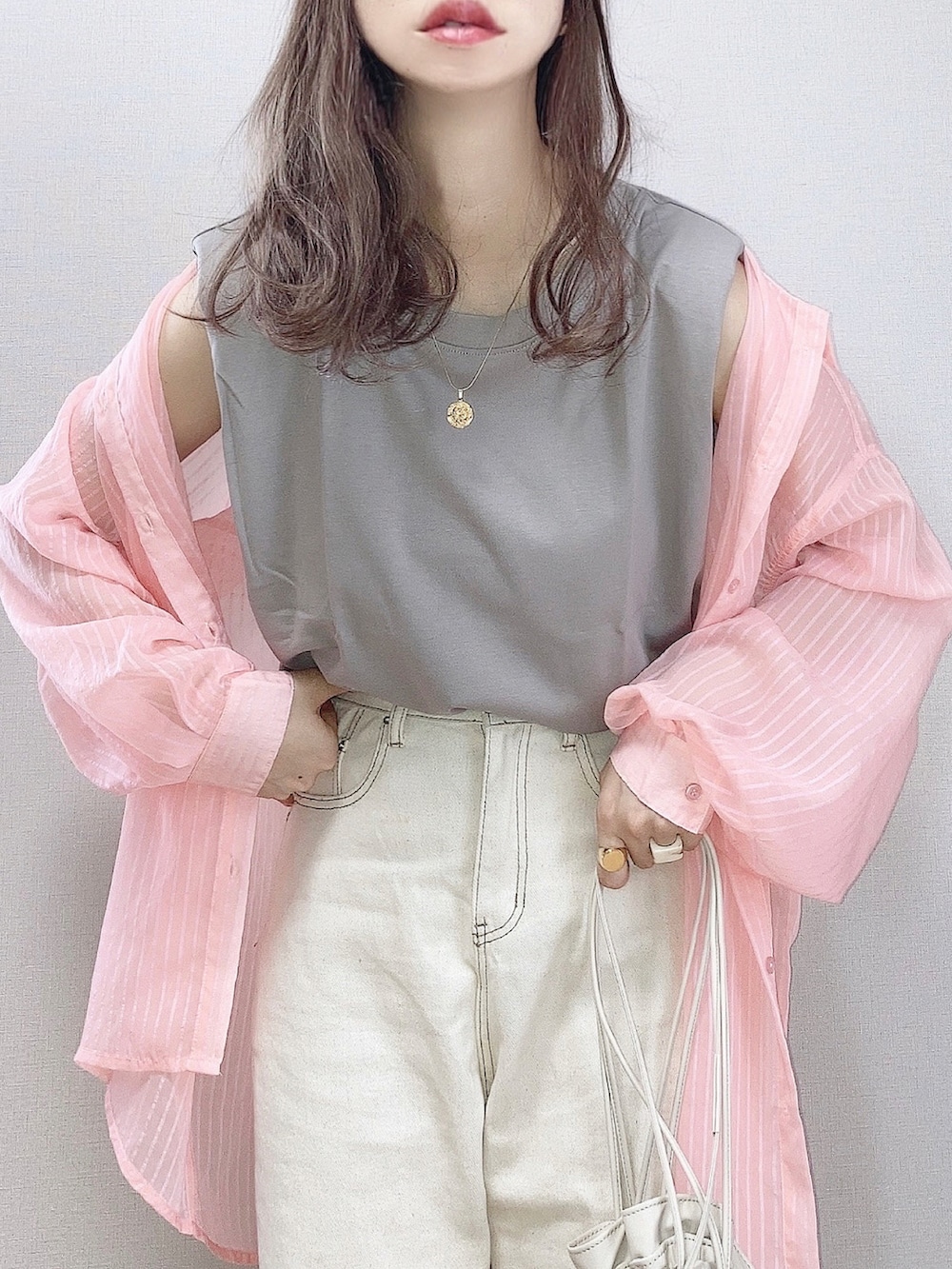 ピンク系のシャツ/ブラウス、ブラウン系のタンクトップ、ベージュ系のデニムパンツを着用したレディースの夏コーディネートの2枚目の写真