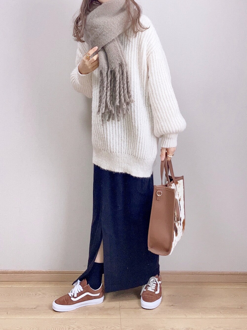 ホワイト系のカーディガン/ボレロ、ブラック系のスカート、ブラウン系のトートバッグを着用したレディースの冬コーディネートの2枚目の写真