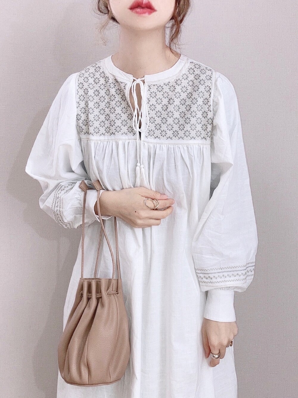 ホワイト系のワンピース、ベージュ系のハンドバッグ、ブラウン系のパンプスを着用したレディースの春コーディネートの2枚目の写真