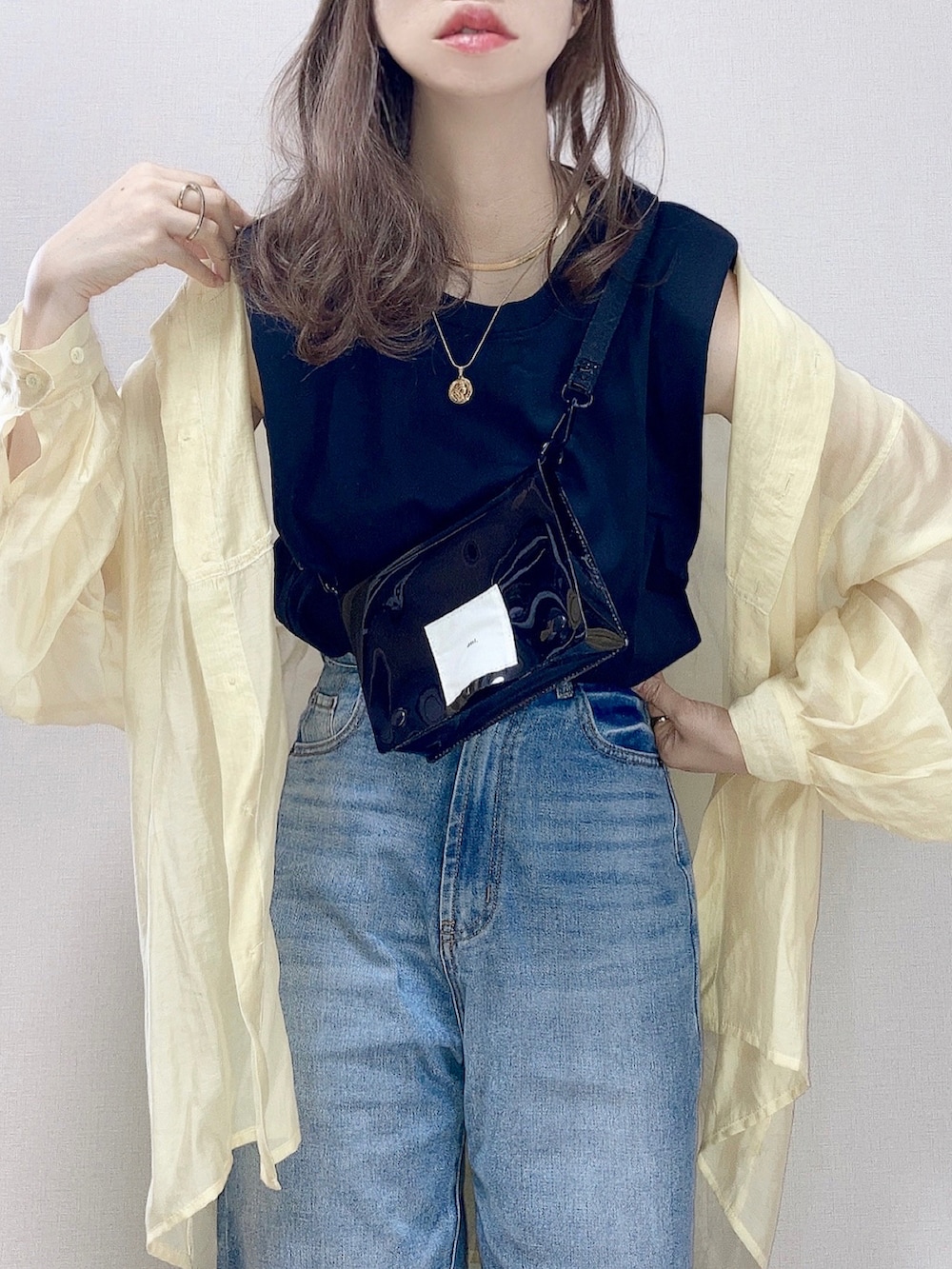 イエロー系のシャツ/ブラウス、ブラック系のタンクトップ、ブルー系のデニムパンツを着用したレディースの春コーディネートの2枚目の写真