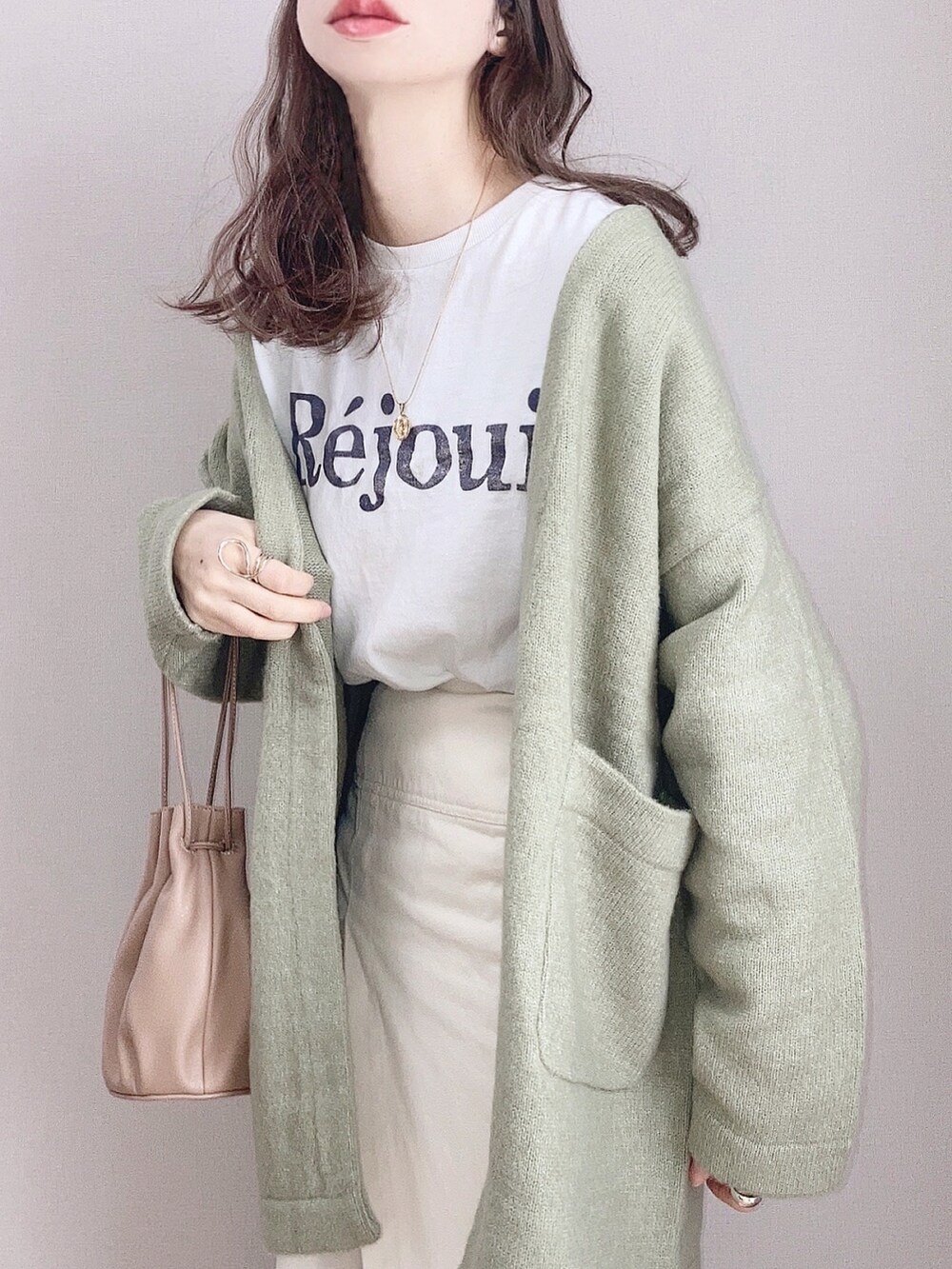 グリーン系のカーディガン/ボレロ、ホワイト系のTシャツ/カットソー、ホワイト系のスカートを着用したレディースの冬コーディネートの3枚目の写真