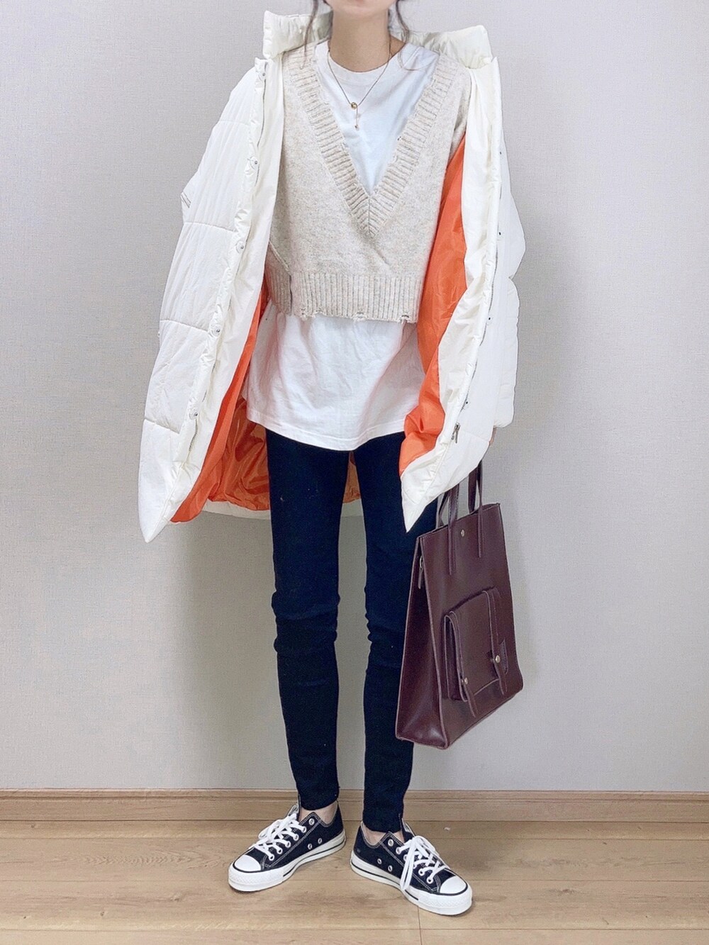 ホワイト系のダウンジャケット/コート、ベージュ系のニット/セーター、ブラック系のデニムパンツを着用したレディースの秋コーディネートの2枚目の写真