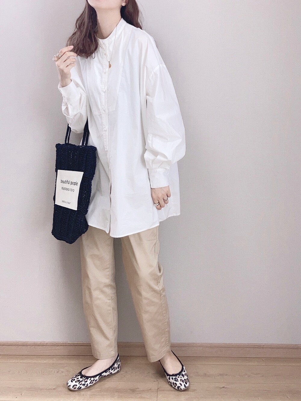 ベージュ系のチノパンツ、ホワイト系のシャツ/ブラウス、ブラック系のトートバッグを着用したレディースの春コーディネートの2枚目の写真