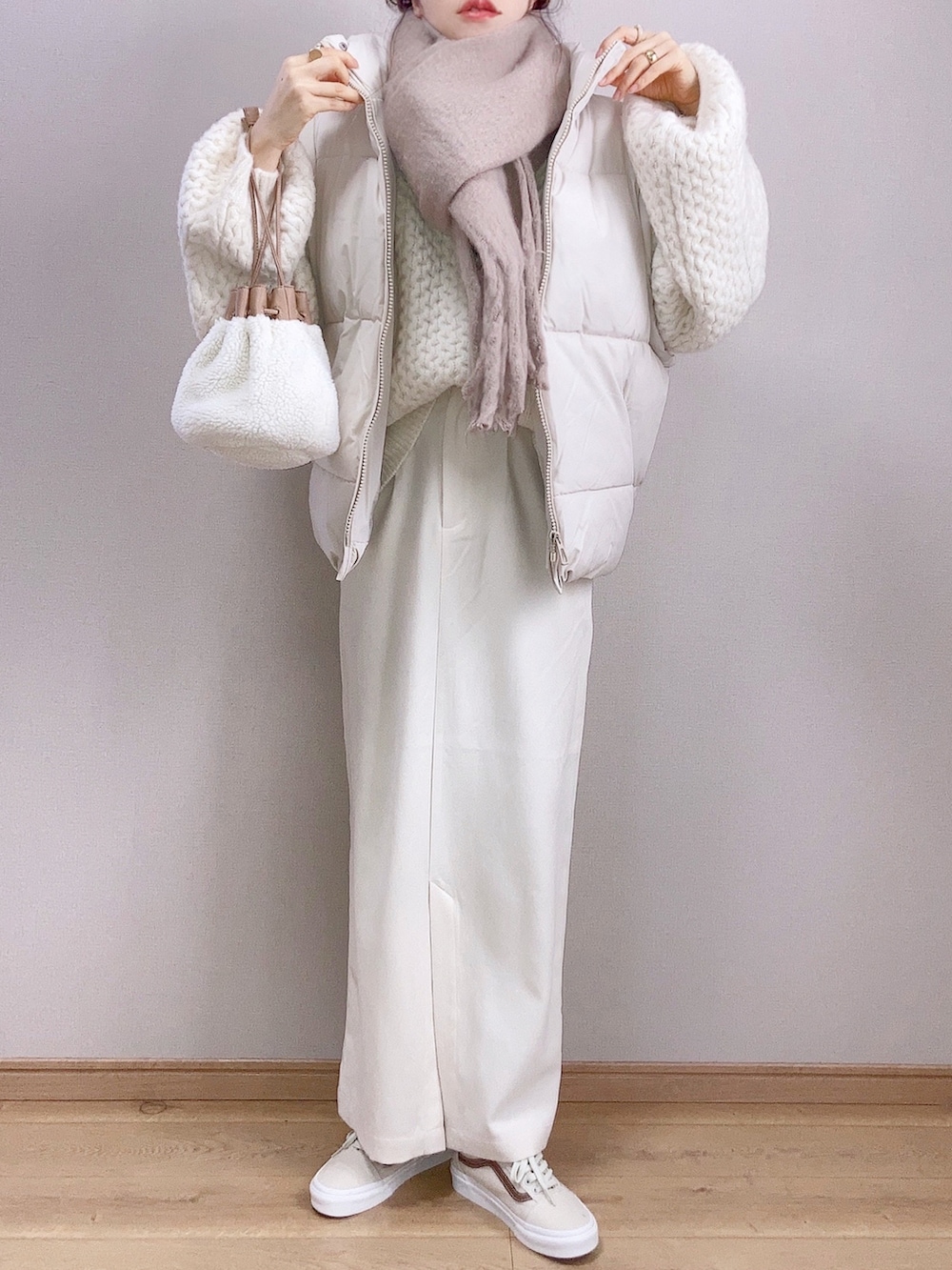 ベージュ系のダウンベスト、ホワイト系のニット/セーター、ホワイト系のスカートを着用したレディースの冬コーディネートの2枚目の写真