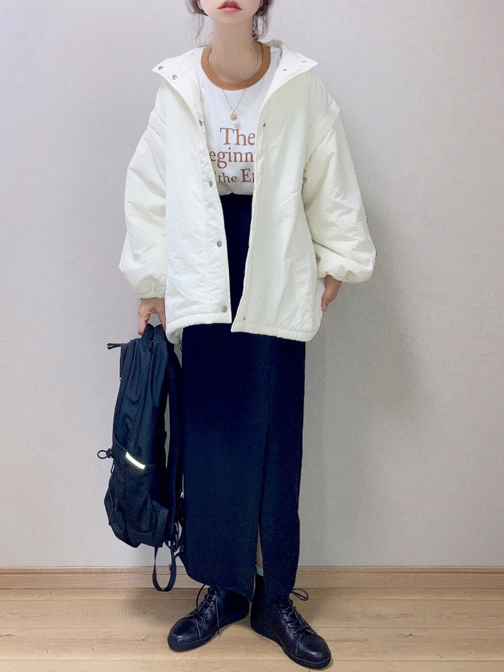 ホワイト系のダウンジャケット/コート、イエロー系のTシャツ/カットソー、ブラック系のスカートを着用したレディースの秋コーディネートの2枚目の写真