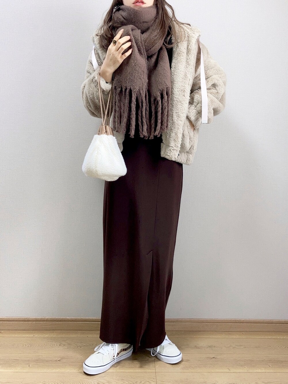 ベージュ系のブルゾン、ブラウン系のスカート、ベージュ系のハンドバッグを着用したレディースの冬コーディネートの2枚目の写真