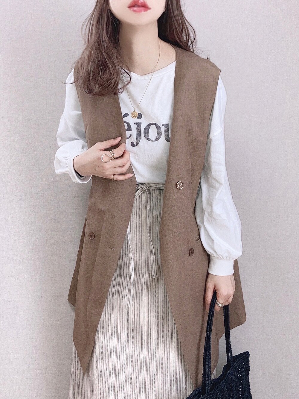 ブラウン系のスカート、ホワイト系のTシャツ/カットソー、ブラウン系のベストを着用したレディースの春コーディネートの2枚目の写真