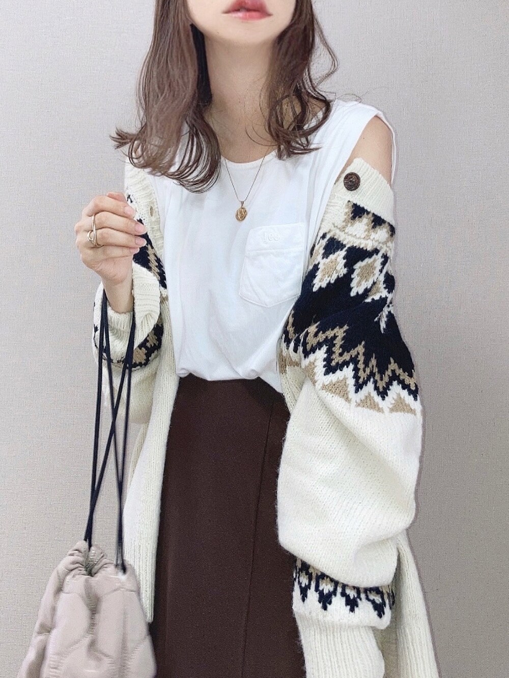 ホワイト系のニット/セーター、ホワイト系のTシャツ/カットソー、ブラウン系のスカートを着用したレディースの秋コーディネートの3枚目の写真