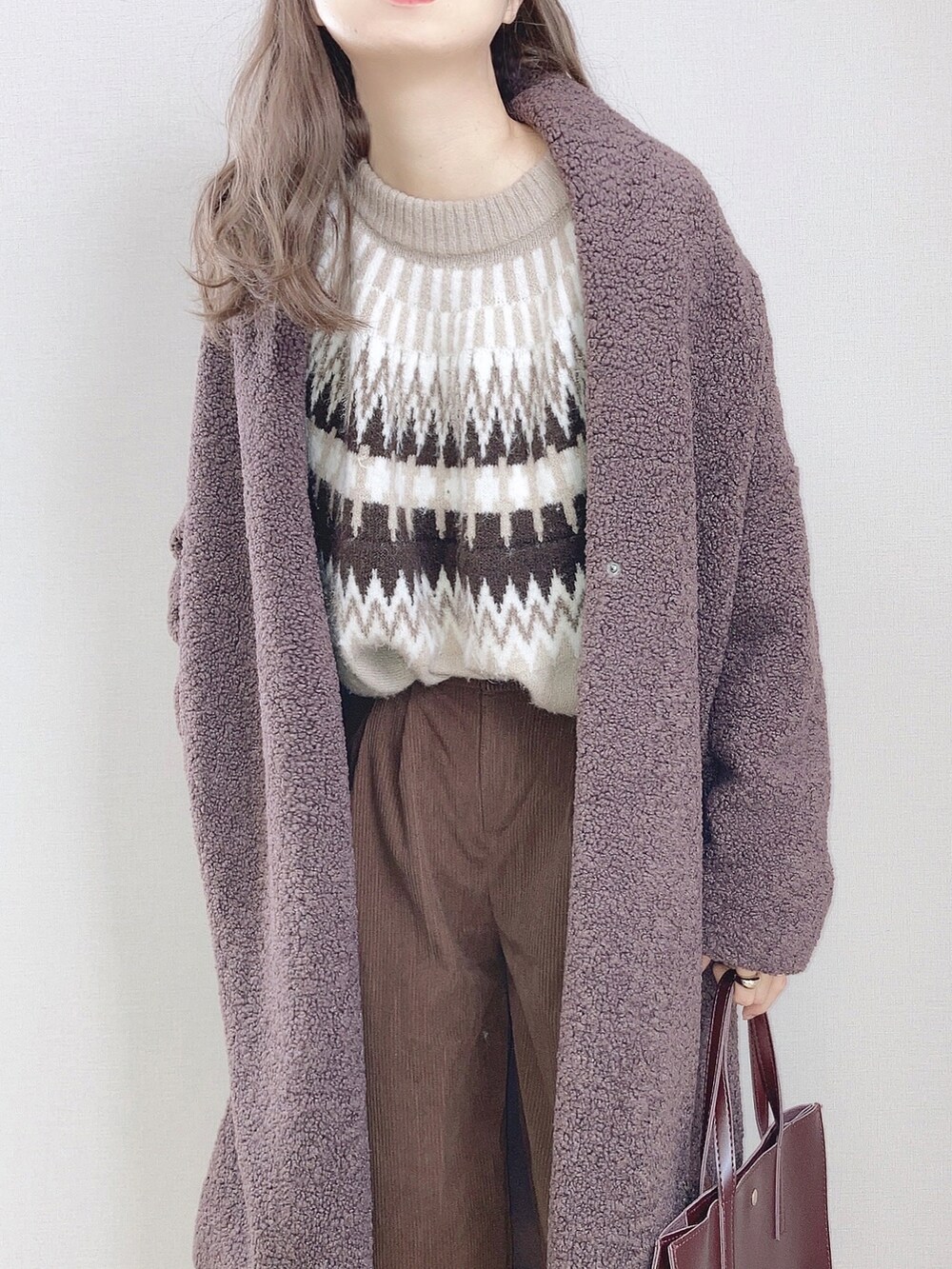 ブラウン系のノーカラーコート、ベージュ系のニット/セーター、ブラウン系のその他パンツを着用したレディースの冬コーディネートの2枚目の写真