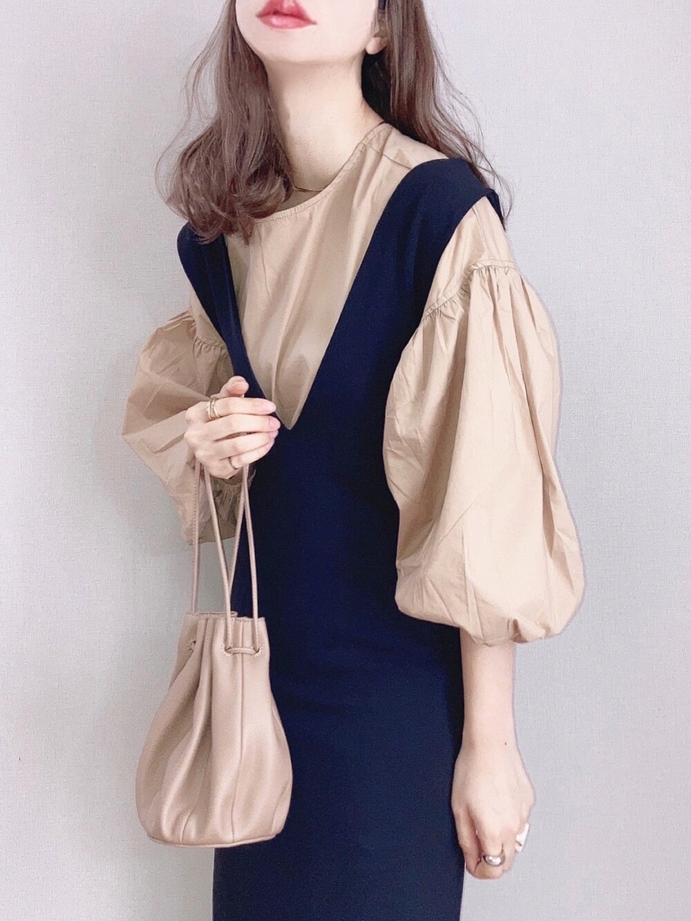 ベージュ系のシャツ/ブラウス、ブラック系のワンピース、ベージュ系のハンドバッグを着用したレディースの春コーディネートの2枚目の写真