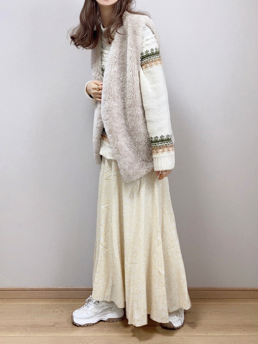 イエロー系のスカート、グリーン系のニット/セーターを着用したレディースの冬コーディネートの2枚目の写真