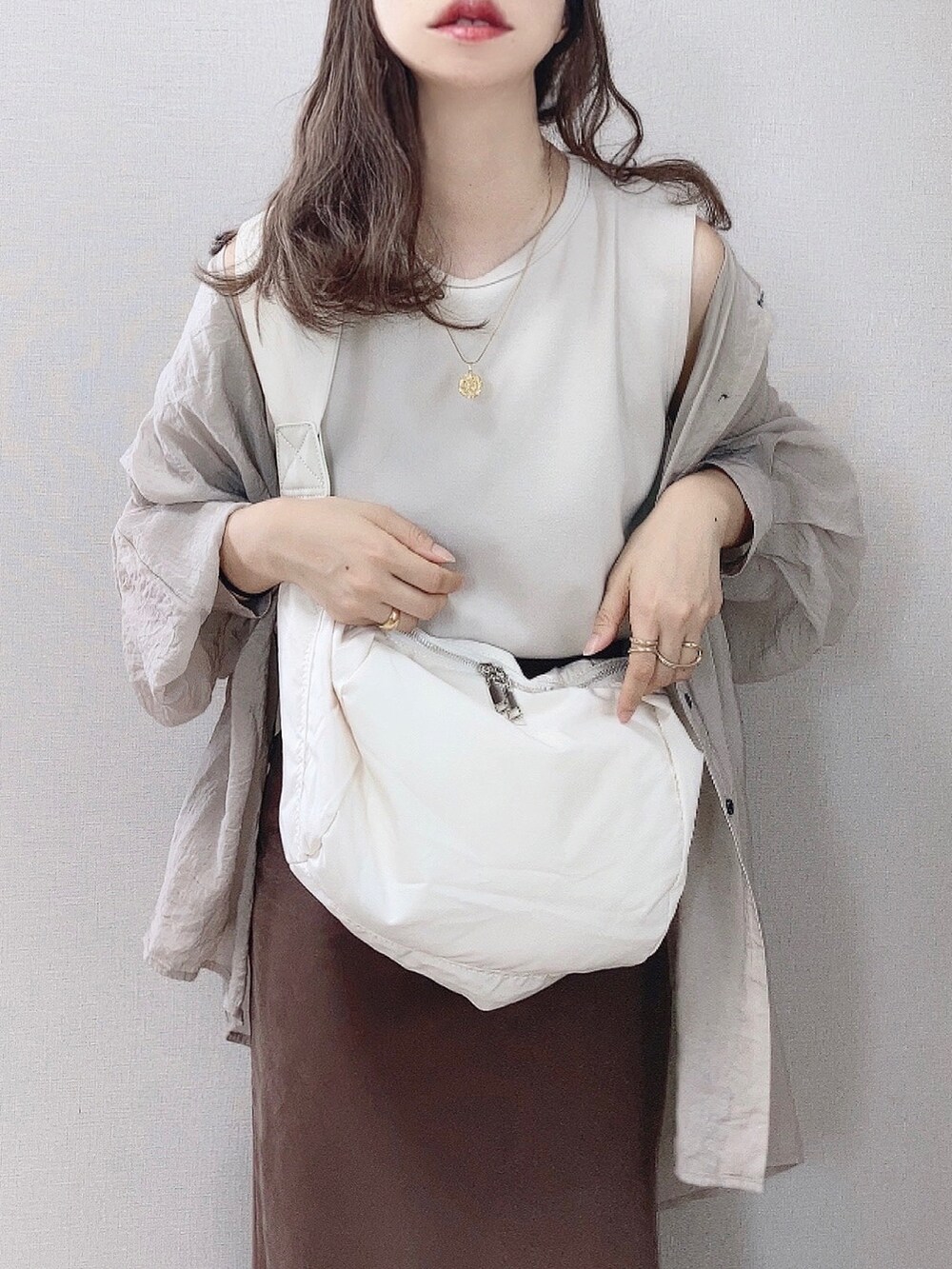 ホワイト系のショルダーバッグ、ベージュ系のシャツ/ブラウス、ベージュ系のタンクトップを着用したレディースの夏コーディネートの2枚目の写真