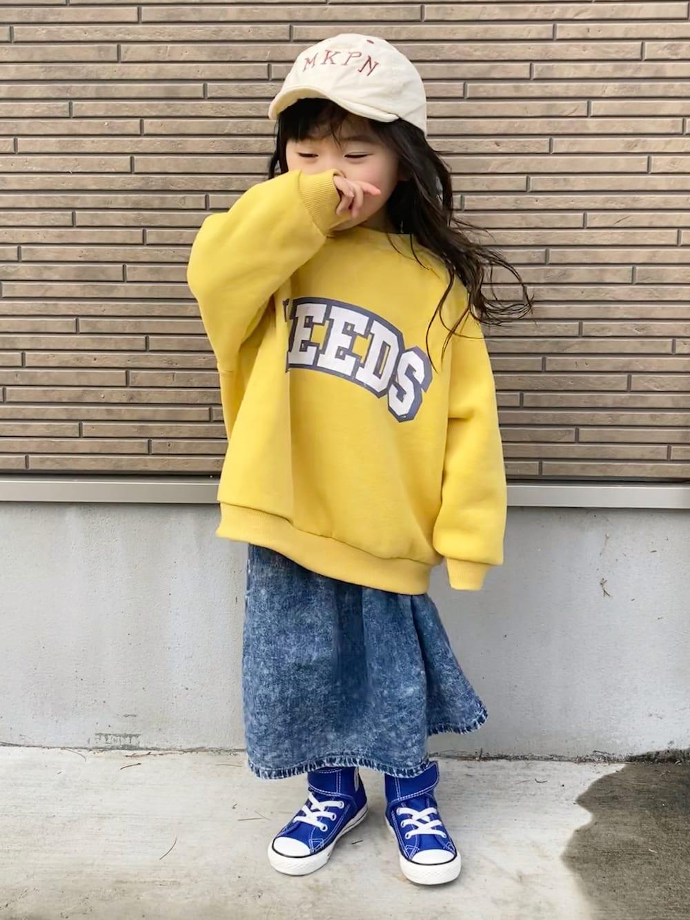 イエロー系のスウェット、ブルー系のデニムスカート、ブルー系のスニーカーを着用したキッズの春コーディネートの4枚目の写真
