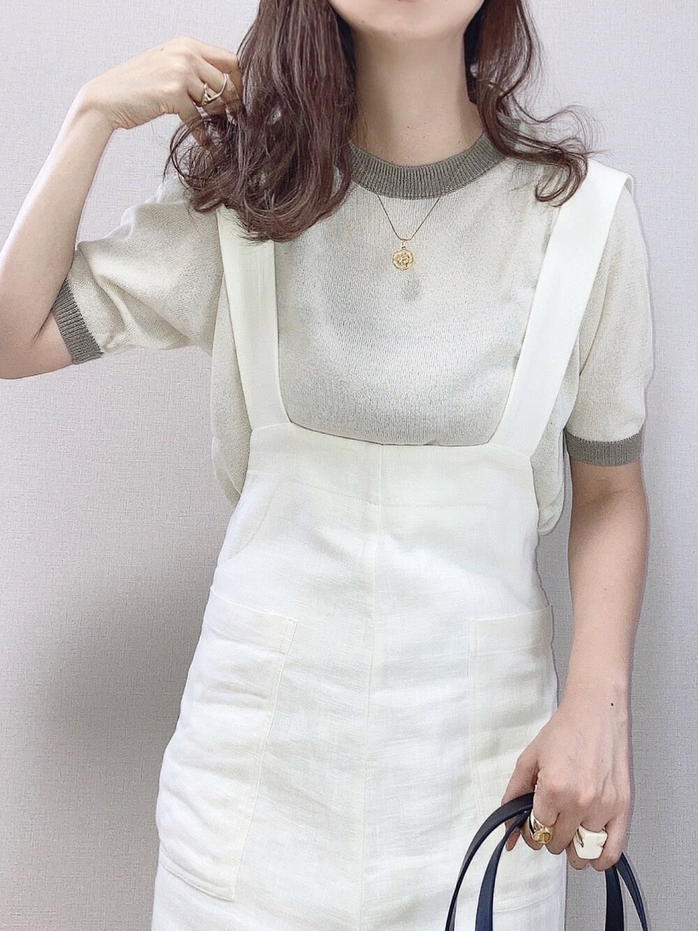 ベージュ系のニット/セーター、ホワイト系のサロペット/オーバーオール、ブラック系のかごバッグを着用したレディースの夏コーディネートの2枚目の写真