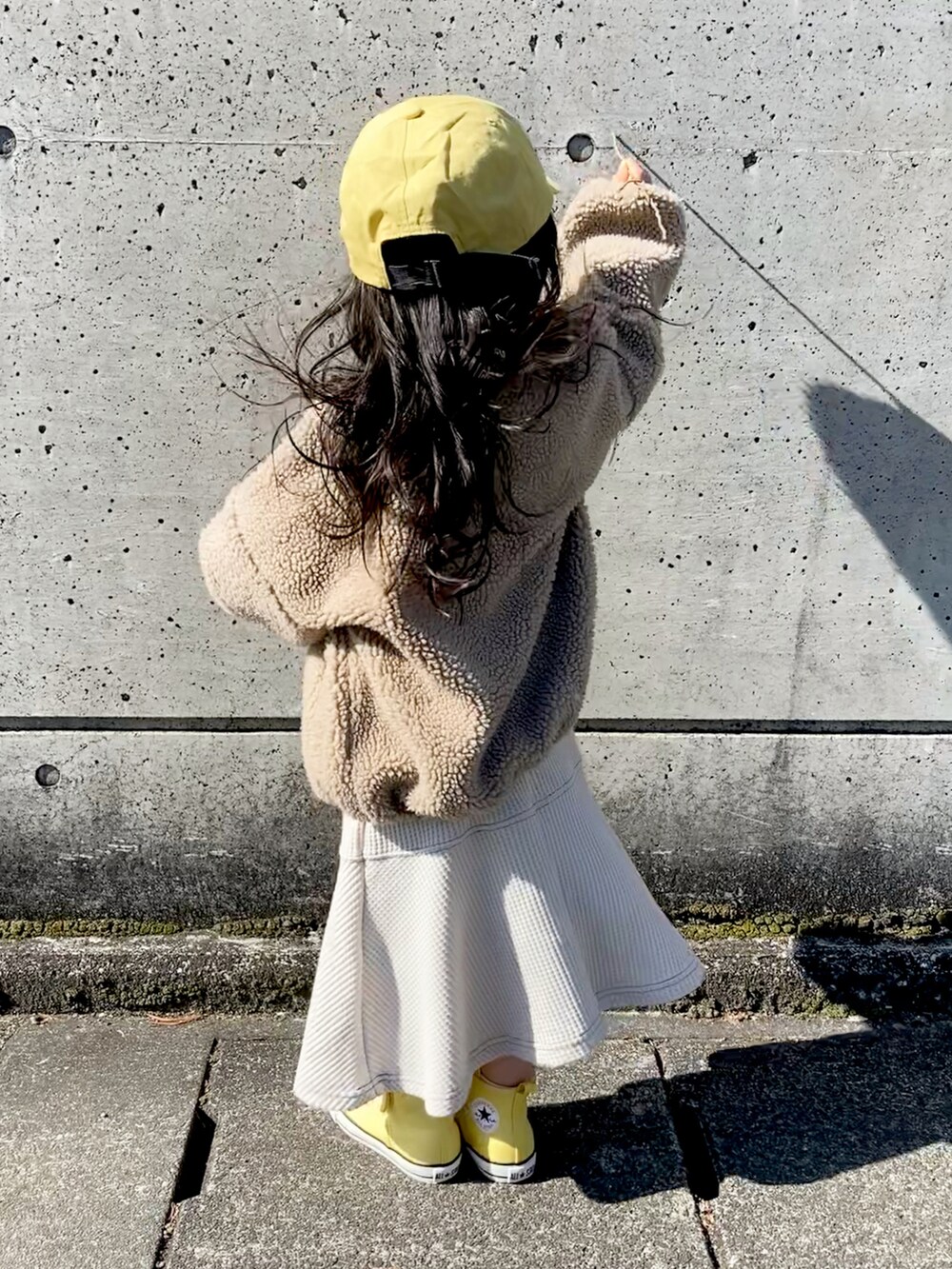 ベージュ系のワンピース、イエロー系のスニーカー、イエロー系のキャップを着用したキッズの冬コーディネートの4枚目の写真