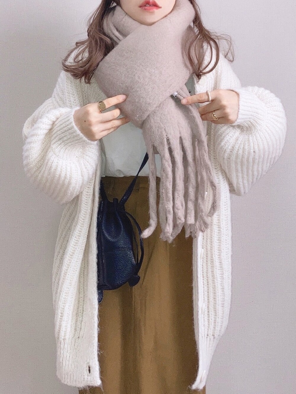 ホワイト系のカーディガン/ボレロ、ブラウン系のスカート、ブラック系のショルダーバッグを着用したレディースの冬コーディネートの3枚目の写真