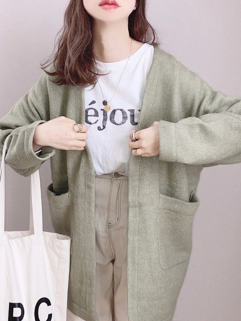 グリーン系のカーディガン/ボレロ、ホワイト系のTシャツ/カットソー、ホワイト系のトートバッグを着用したレディースの春コーディネートの2枚目の写真