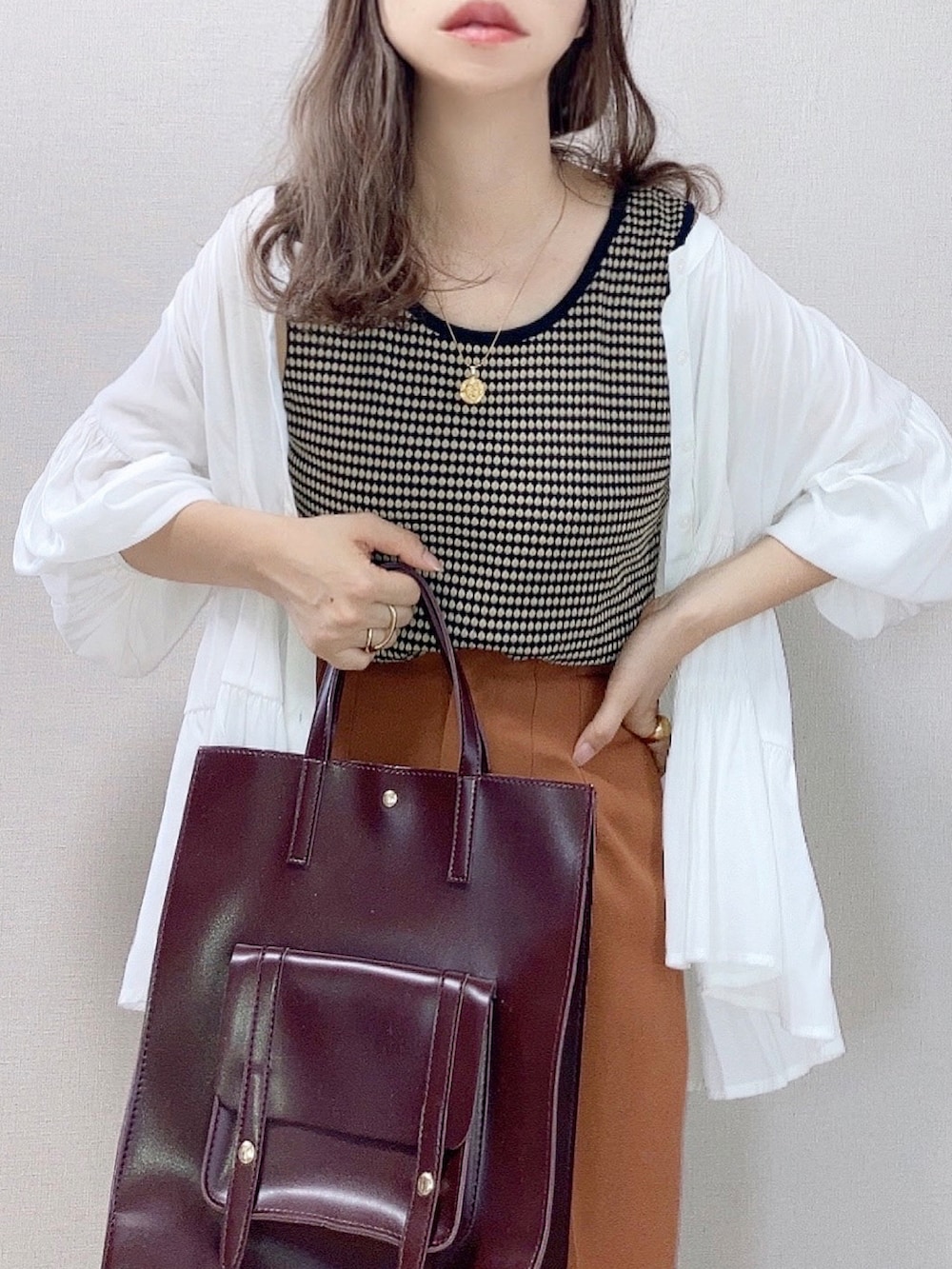 ブラック系のタンクトップ、ブラウン系のハンドバッグ、ホワイト系のサンダルを着用したレディースの夏コーディネートの3枚目の写真