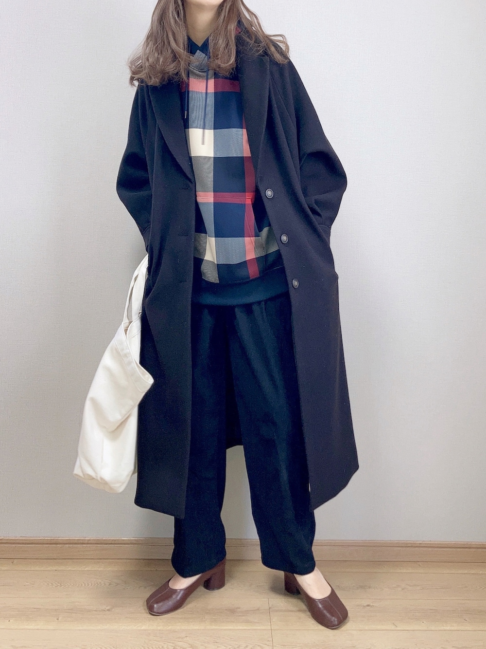 ブルー系のパーカー、ブラック系のチェスターコート、ブラック系のその他パンツを着用したレディースの冬コーディネートの2枚目の写真