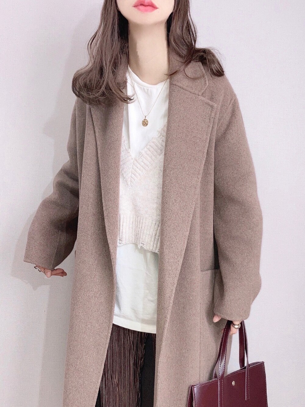ブラウン系のピーコート、ホワイト系のニット/セーター、ホワイト系のTシャツ/カットソーを着用したレディースの冬コーディネートの2枚目の写真