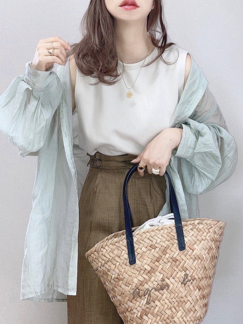 グリーン系のシャツ/ブラウス、ベージュ系のタンクトップ、ブラック系のかごバッグを着用したレディースの夏コーディネートの2枚目の写真