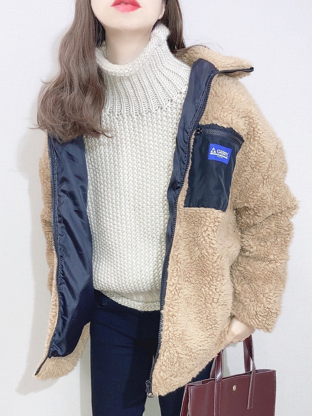 ベージュ系のブルゾン、ホワイト系のニット/セーター、ブラック系のデニムパンツを着用したレディースの冬コーディネートの2枚目の写真