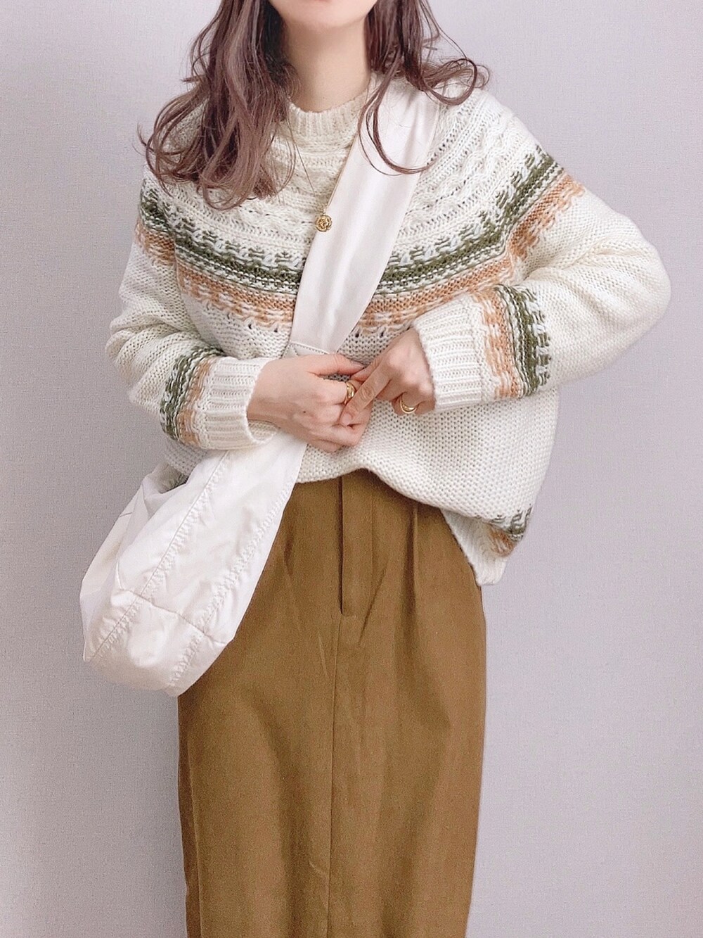 グリーン系のニット/セーター、ホワイト系のショルダーバッグ、ブラウン系のスカートを着用したレディースの冬コーディネートの3枚目の写真